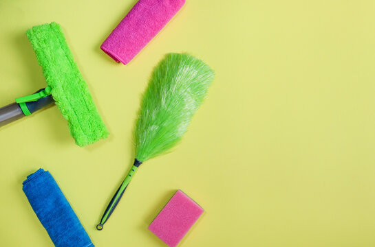 household items on yellow

Rags, sponge, windshield wiper and dust brush are on the left against a yellow background with offset text on the right, close-up from above.
