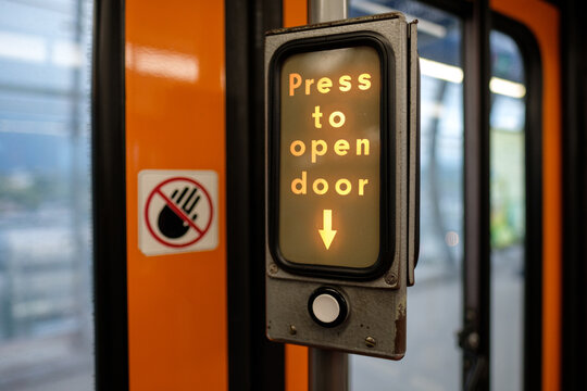 Old illuminated 'Press to open door' sign on subway train car