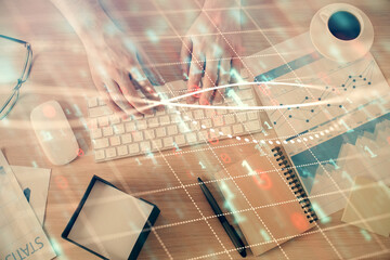 Multi exposure of man's hands typing over computer keyboard and forex graph hologram drawing. Top view. Financial markets concept.