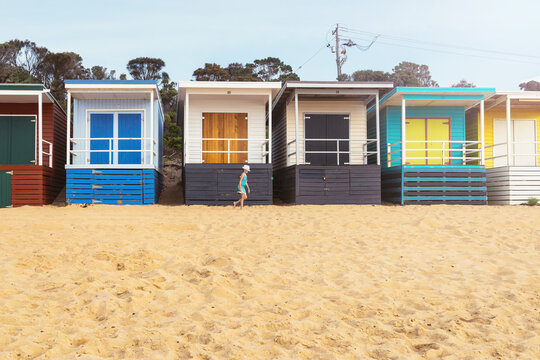 tween girl walking in front of a row of bathing huts at Mt Marth