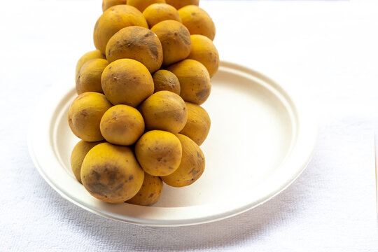 longong yellow fruit branch lies on a white plate on a white background