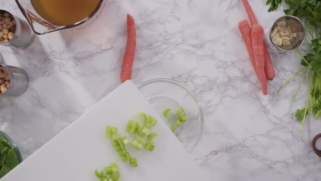 Curring vegetables on a white cutting board to cook vegetarian white bean soup.