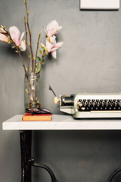 a marble hall table with an old typewriter, novel, glasses and f