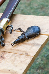 old flintlock rifle close-up with an iron bottle of powder flask