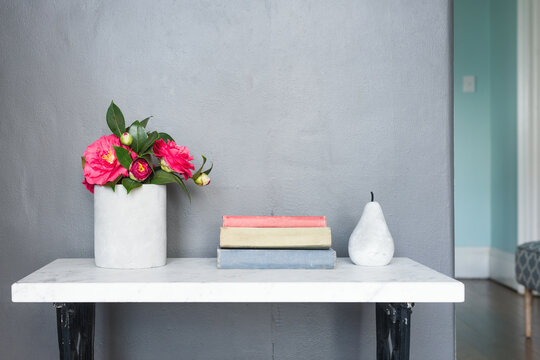 hall table with concrete decor items, flowers and books