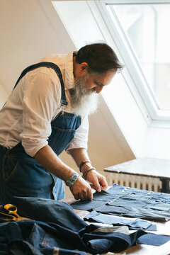 Indoor Portrait of Fashionable Senior Male Tailor Creating Denim Patchwork