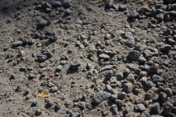 Different grey stones (gravel) on surface of the dirt road.