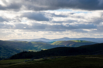 Obraz premium a mountainous view of the mountains in Powys looking into Gwyneth with the rolling hills and mountains lit up by the sunlight