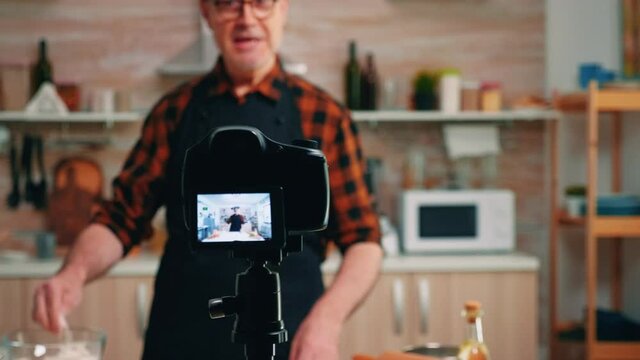 Close up of camera streaming live culinary podcast. Retired blogger chef influencer using internet technology communicating, shooting blogging on social media with digital equipment