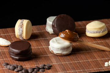 
Artisanal alfajores of cornstarch with coconut, white chocolate and dark chocolate with dulce de leche on wooden mat