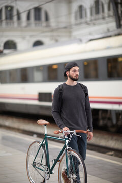 Young man with bicycle walking on a railway platform
