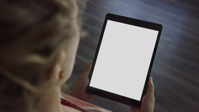 Woman holds tablet device in portrait orientation with blank white screen