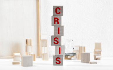 Falling wooden blocks with the word Crisis. Instability of business and economy.