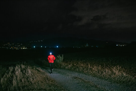 Man running on a field path at night.