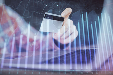 Double exposure of man hands holding a credit card and Forex graph drawing. Stock trading and digital fintech in Internet E-commerce concept.