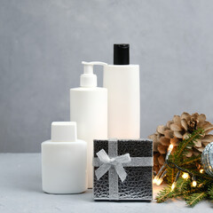 Fototapeta na wymiar Blank white cosmetics bottles and Christmas gift. Body and hair care concept, Christmas sale of beauty products.