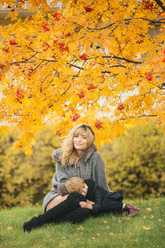 A mother and son sitting underneath a mountain ash tree looking cozy