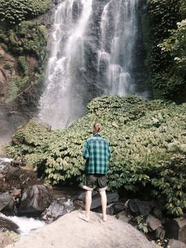 Young man standing in front of waterfall