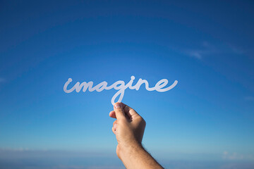 Imagine. Paper word on blue sky