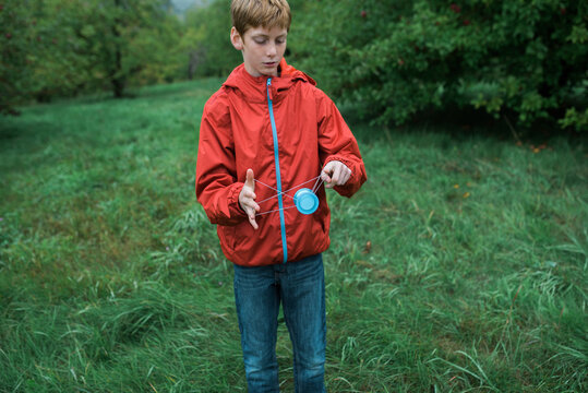 teen playing yoyo in an orchard