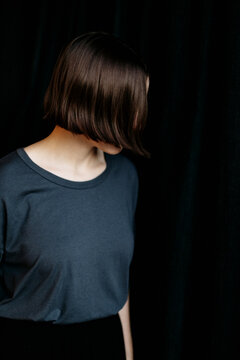Girl in dark navy shirt against black wall
