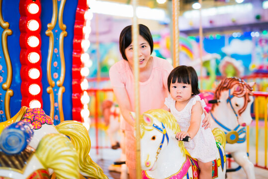 mother with baby daughter on merry-go-round