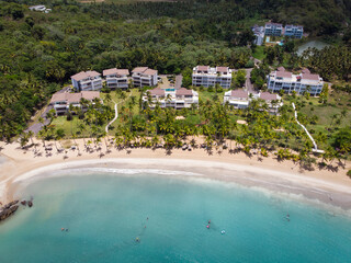 Aerial drone view of tropical beach residence (condo) at the paradise beach with the pool, palm trees and blue water of Atlantic Ocean, Las Terrenas, Samana, Dominican Republic