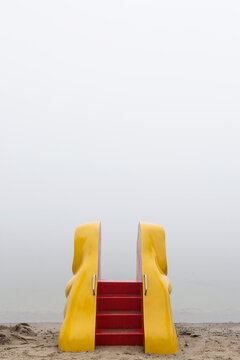 Yellow elephant slide on a beach on a foggy morning
