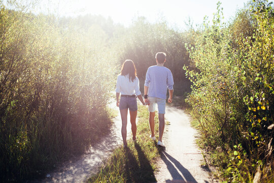 Pretty young stylish couple in love walking on the road in summer forest