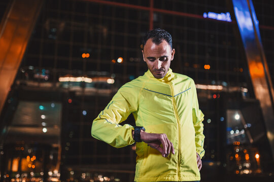 Handsome athlete in yellow checking time - Powered by Adobe