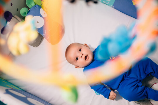 Cute adorable newborn baby amazed with his hanged toy