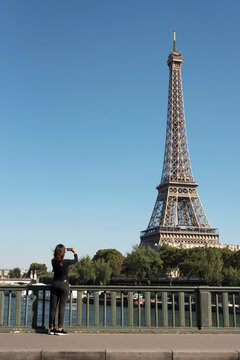 A young woman taking photos of Eiffel Tower with an phone in Paris
