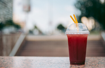 Red raspberry drink in a plastic glass with a straw