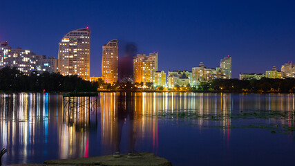 Obraz premium A guy stands on the banks of the Dnieper river against the background of a bright night embankment
