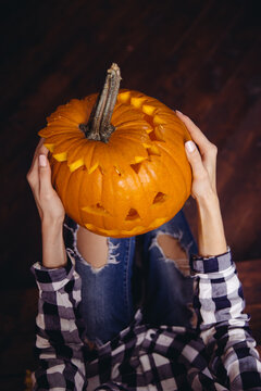 Top view of incognito female holding jack o lantern.