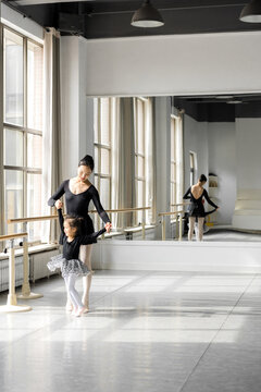 Female ballet instructor teaching girl in ballet studio