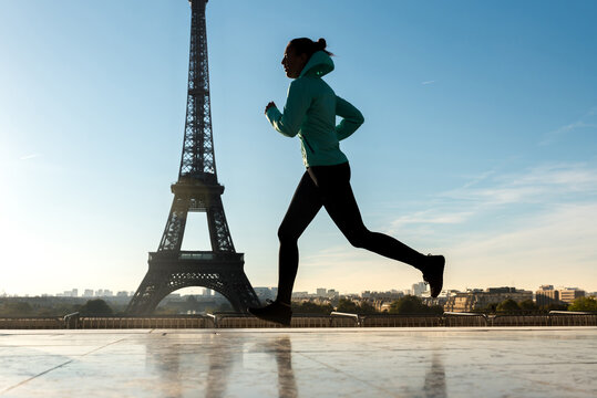 Young woman running on the Eiffel Tower background.