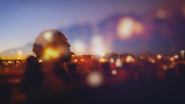 Silhouette of bearded man against city lights at night
