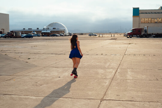 Woman in blue dress on roller skates riding around an airfield