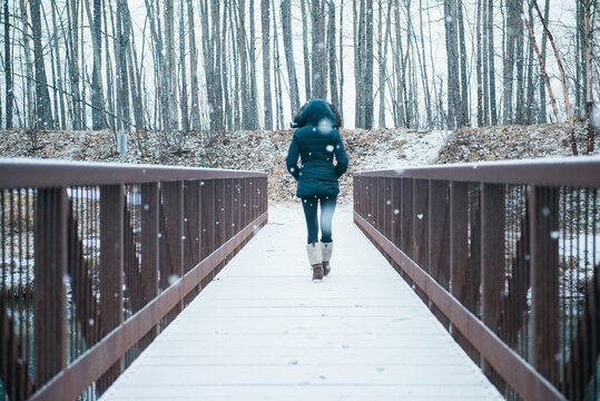 Anonymous women walking across snowy bridge
