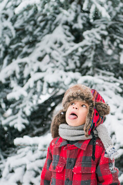 child trying to catch snowflakes on his tongue