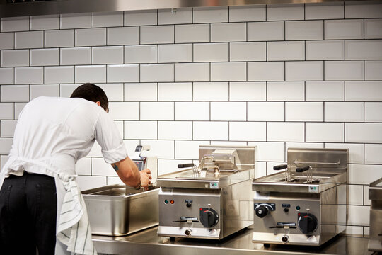 Male Chef Cooking In Commercial Kitchen