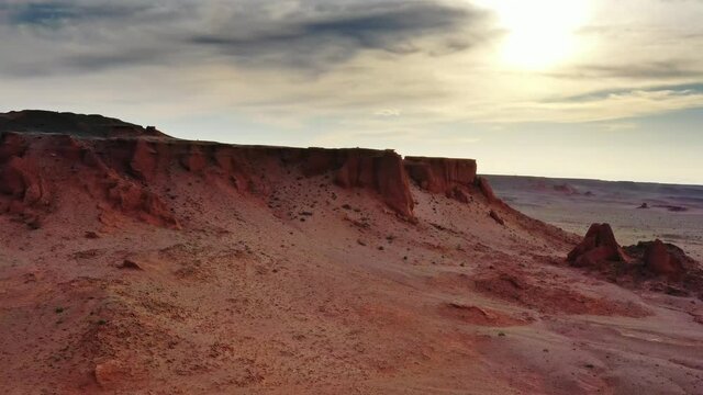 Aerial around view of the Bayanzag flaming cliffs at sunset in Mongolia, found in the Gobi Desert, 4k