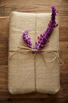 Still life of burlap wrapped present with purple flower