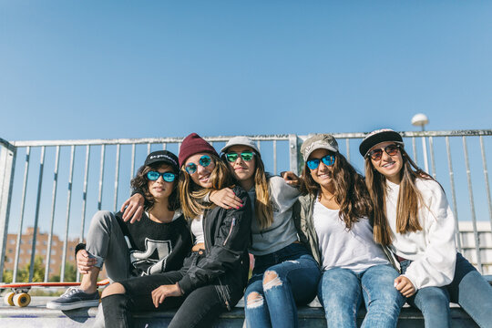 Five girls sit in a skateboard park.