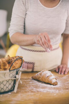 Young woman's hands powdering sugar on croasant