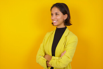 Young hispanic businesswoman wearing casual turtleneck sweater and jacket crossing arms looking aside having a nice conversation