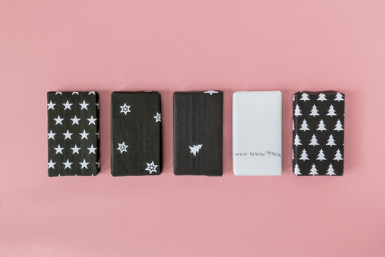 Christmas presents wrapped in self-made black and white paper on pink background