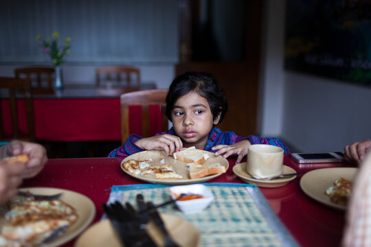 Little girl having breakfast unwillingly