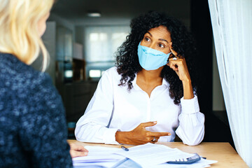 Two women having a financial business consultation with masks and social distancing due to coronavirus